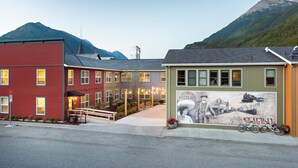 A street with buildings, a mural, and a mountain in the background. -  Holland America Skagway Inn (Skagway)