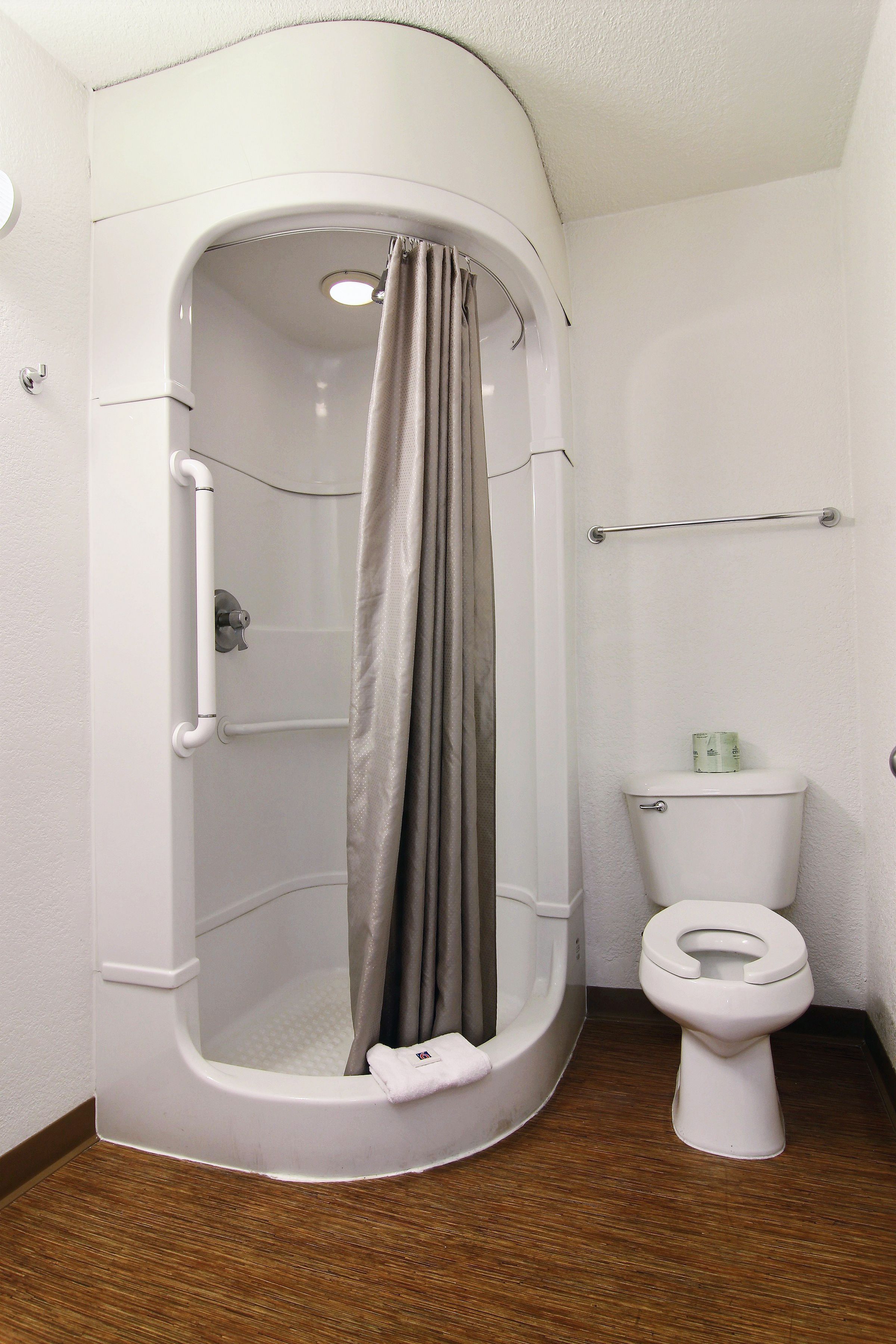 Un petit espace douche fermé, équipé de toilettes et d’un porte-serviettes.