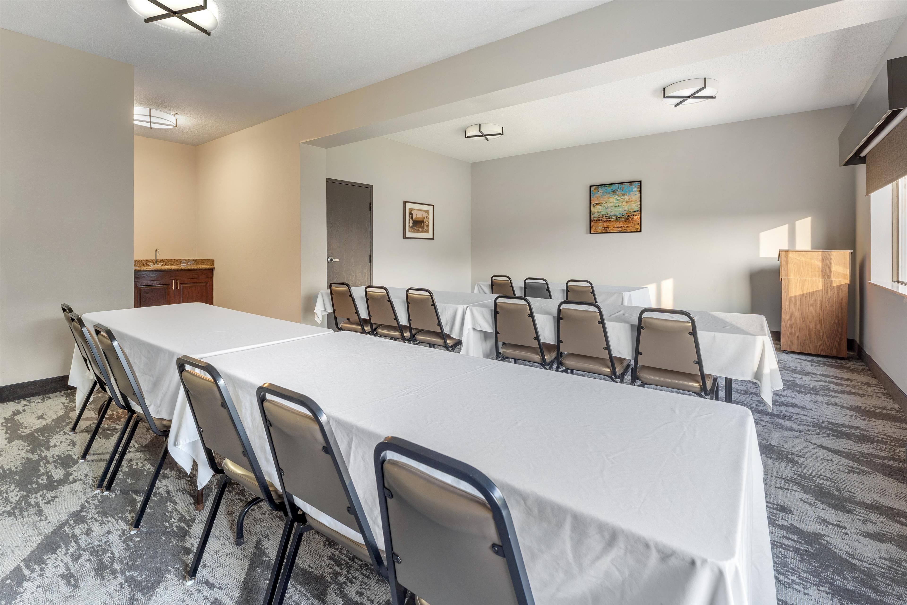 Un salón de conferencias con una larga mesa, sillas y una pequeña kitchenette.