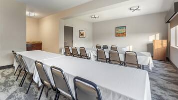 Un salón de conferencias con una larga mesa, sillas y una pequeña kitchenette.