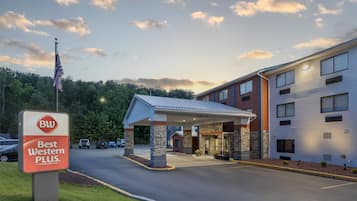 A Best Western Plus hotel with a covered entrance, a parking lot, and a flagpole with an American flag.