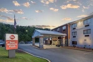 A Best Western Plus hotel with a covered entrance, a parking lot, and a flagpole with an American flag. - Best Western Plus Executive Inn (St. Marys)