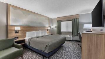 A hotel room with a large bed, a desk, a chair, a flat-screen TV, and a large window with curtains.