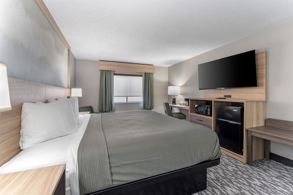 A hotel room with a large bed, a flat-screen TV mounted on the wall, a microwave, and a refrigerator. - Best Western Plus Executive Inn (St. Marys)