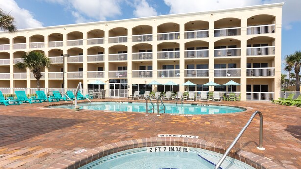 A hotel with a swimming pool, multiple balconies, and lounge chairs. - Hampton Inn St. Augustine Beach (St. Augustine)