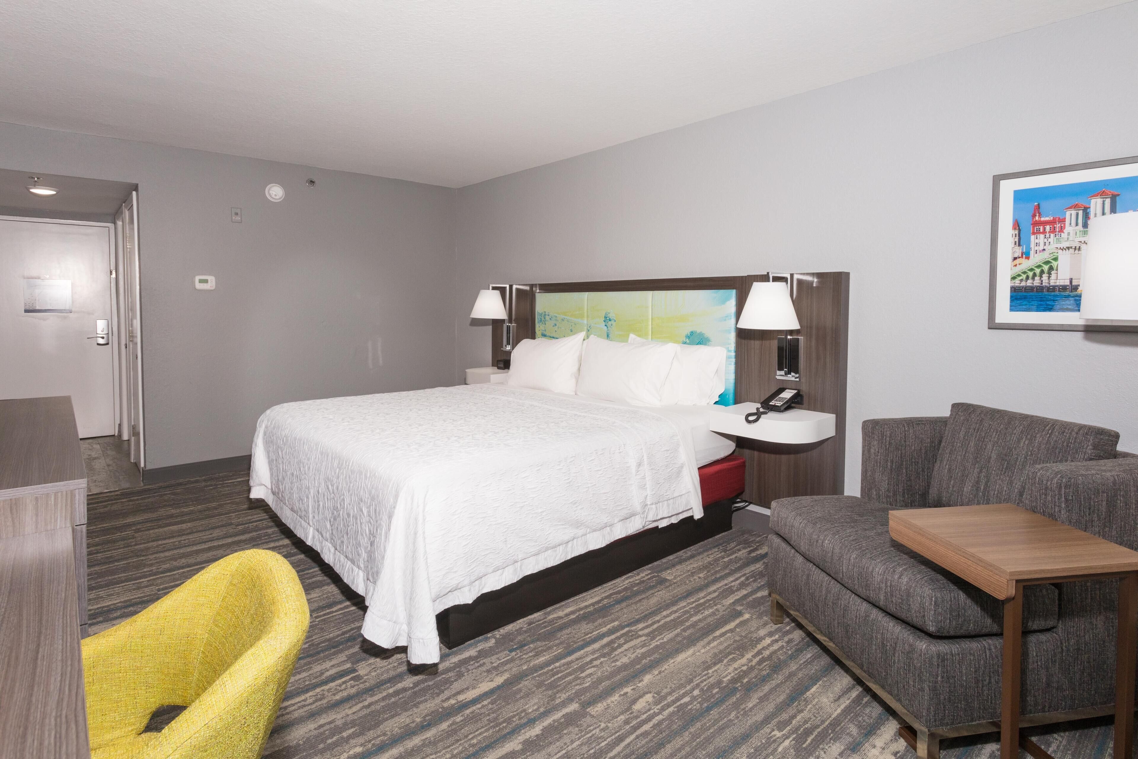 Une chambre d’hôtel avec un lit, un bureau, une chaise et un canapé.