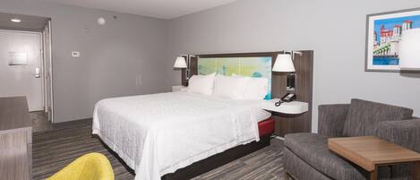 Une chambre d’hôtel avec un lit, un bureau, une chaise et un canapé.