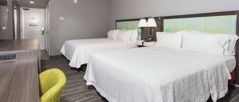 A hotel room with two beds, a desk, and a chair.