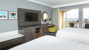 A hotel room with a bed, a desk with a TV, a chair, and a balcony with a view of the ocean. - Hampton Inn St. Augustine Beach (St. Augustine)