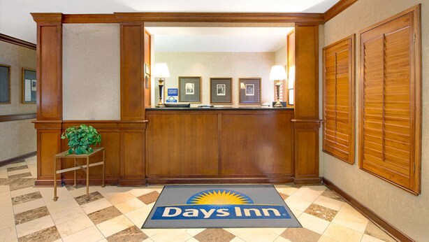 A reception area with a reception desk, framed pictures on the wall, and a 'Days Inn' mat on the floor.