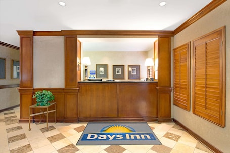A reception area with a reception desk, framed pictures on the wall, and a 'Days Inn' mat on the floor.