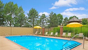 A rectangular outdoor swimming pool with a blue water surface, surrounded by a brick border.