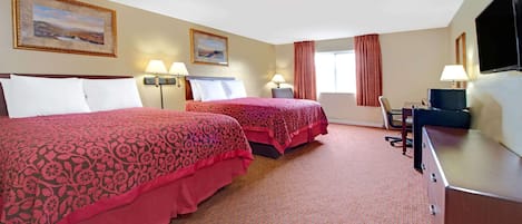 A hotel room with two beds, a desk, a TV, and two lamps.