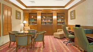 A library with bookshelves, a table with chairs, and a desk with a computer.