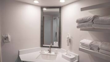 Un baño moderno con lavamanos, espejo y toallero blancos.