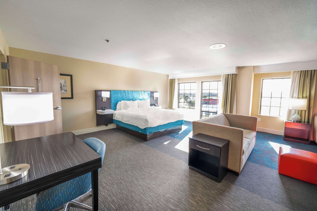 Ein Hotelzimmer mit Bett, Schreibtisch, Sessel, Sofa und kleinem Tisch.