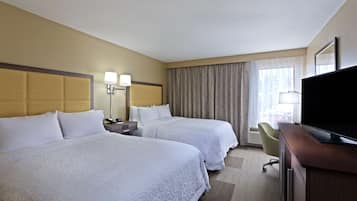 Une chambre d’hôtel avec deux lits, un bureau, une télévision et une chaise.