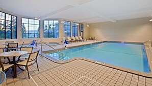 An indoor swimming pool with clear views through large windows, lounge chairs, and a seating area with tables. - Hampton Inn Sault Ste Marie (Sault Ste. Marie)