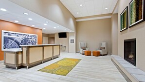 A reception area with a counter, seating, a fireplace, and artwork on the walls. - Hampton Inn Sault Ste Marie (Sault Ste. Marie)