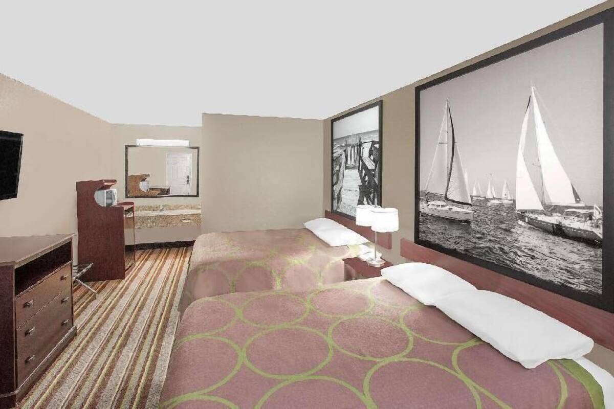 Ein Hotelzimmer mit einem Bett, einem Schminktisch, einem Spiegel und einem großen gerahmten Bild von Segelbooten.