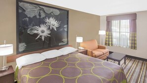 Une chambre d’hôtel avec un grand lit, une chaise, un bureau et une fenêtre avec des rideaux.