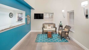 Un couloir avec un mur d’accent bleu, un canapé en osier, une petite table et un tapis à motifs.