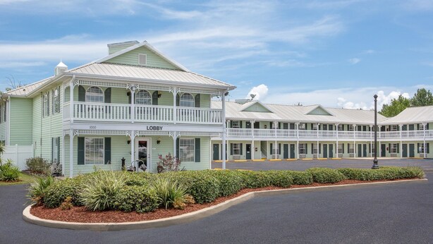 Un motel à deux étages, avec une façade verte et un balcon au deuxième étage.