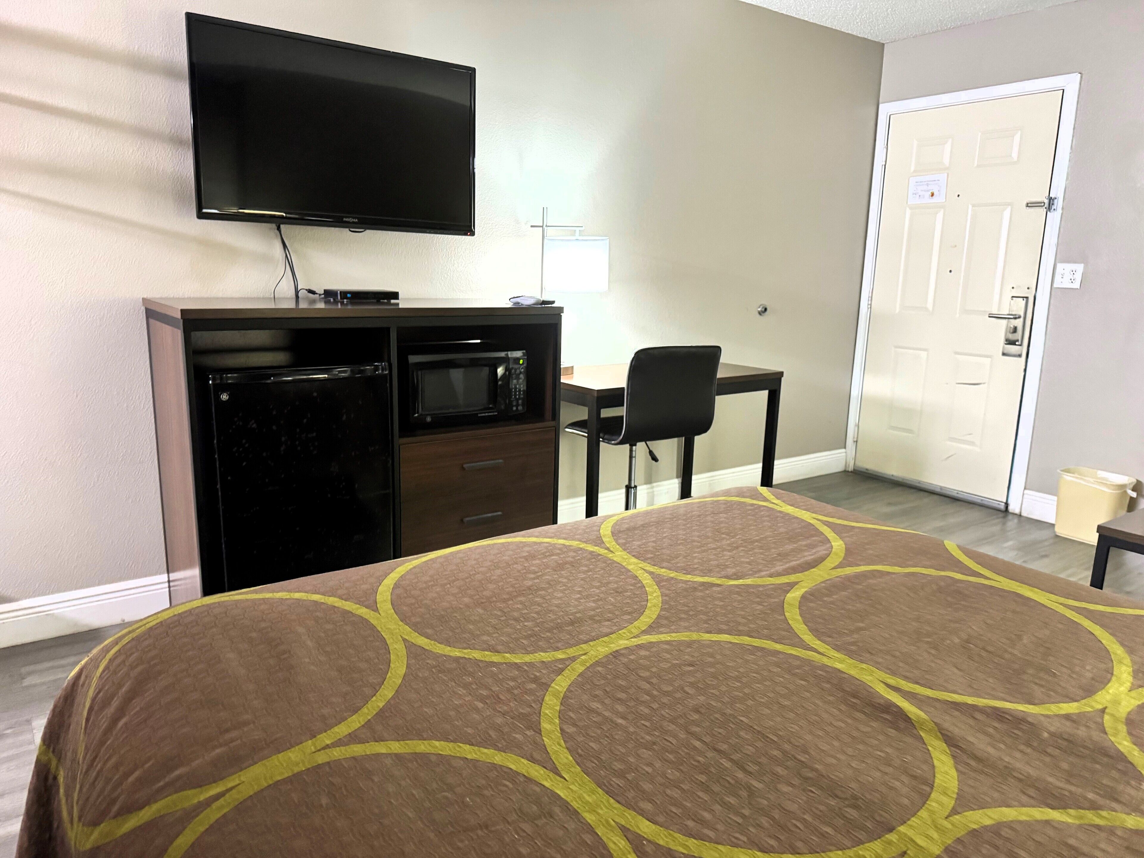 Une chambre d’hôtel équipée d’un lit, d’une télévision, d’un four à micro-ondes, d’un réfrigérateur, d’un bureau et d’une chaise.