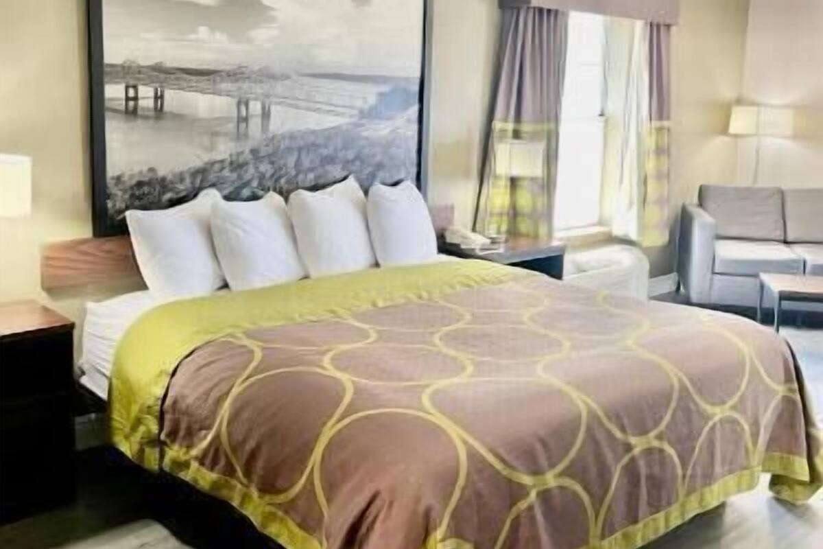 Une chambre d’hôtel avec un lit, un grand tableau, un bureau et une chaise.
