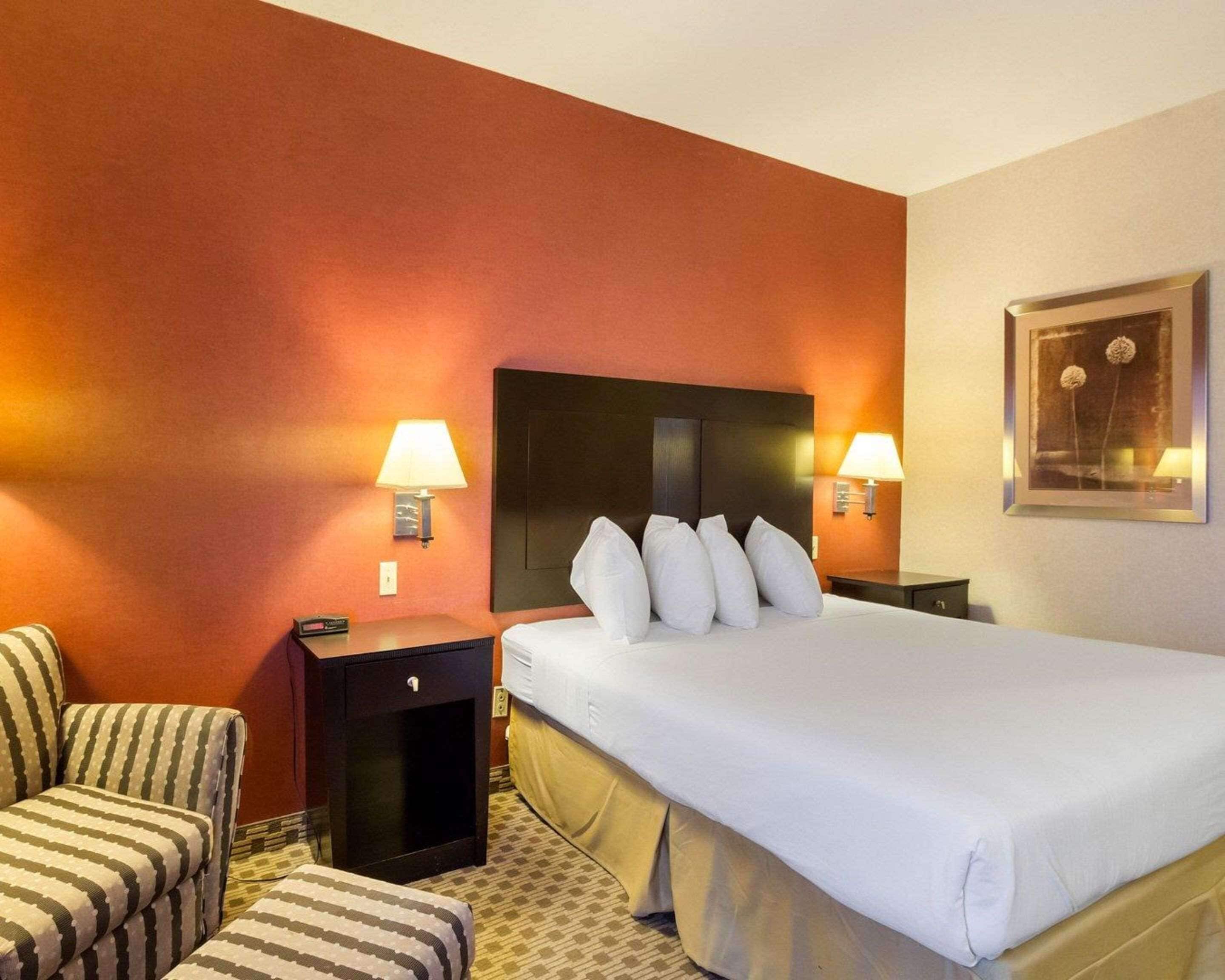 Habitación de hotel con una cama grande, dos mesitas de noche, una silla y un cuadro en la pared.