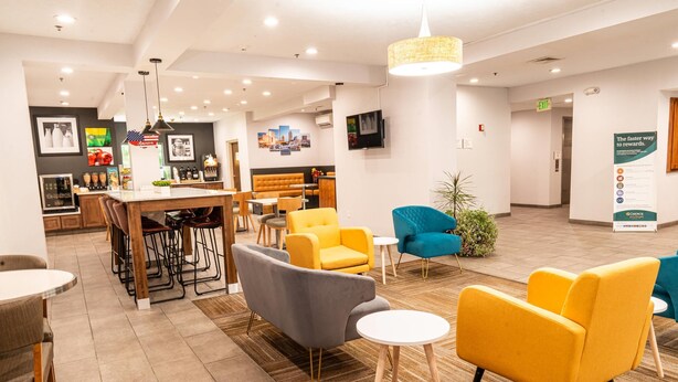 A modern hotel lobby with a bar area, seating arrangements, and a reception desk.