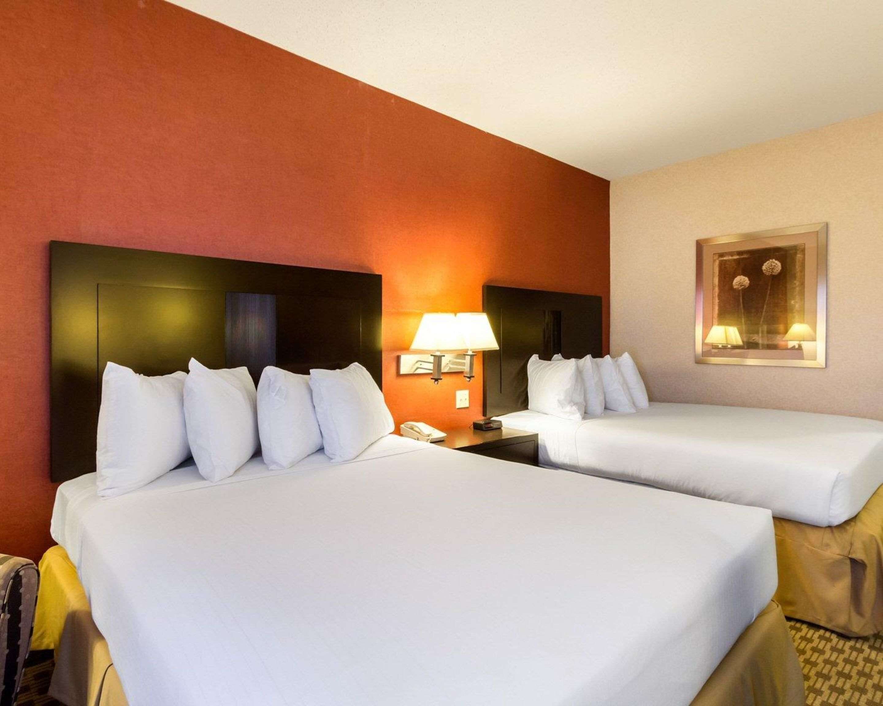 Habitación de hotel con dos camas, una mesita de noche con lámpara y un cuadro en la pared.