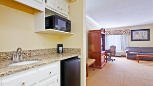 A compact kitchen with a sink, microwave, and coffee maker. There is a dining area with a sofa and a small table. - Holiday Inn Express Ringgold by IHG (Ringgold)
