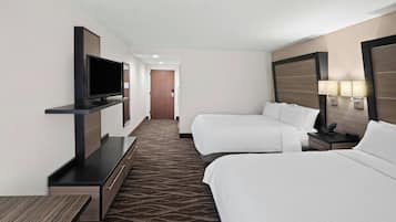 A hotel room with two beds, a flat-screen TV, a desk, and a carpeted floor.