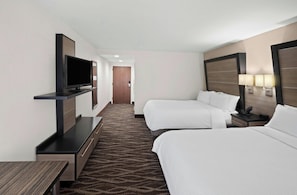 Une chambre d’hôtel avec deux lits, un téléviseur à écran plat, un bureau et un sol recouvert de moquette.