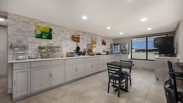 Cozinha moderna com painel de mármore, bancada para refeições rápidas e vista através de amplas janelas.