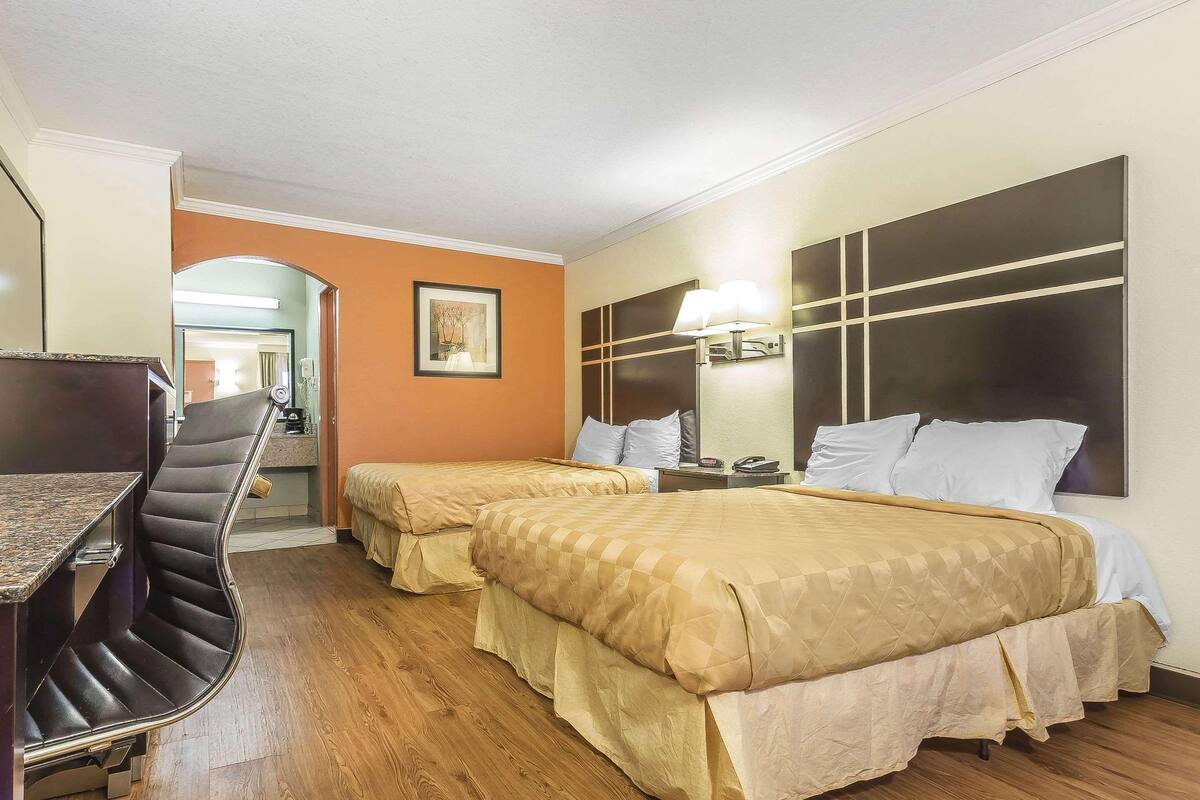 A hotel room with two beds, a desk, and a chair.