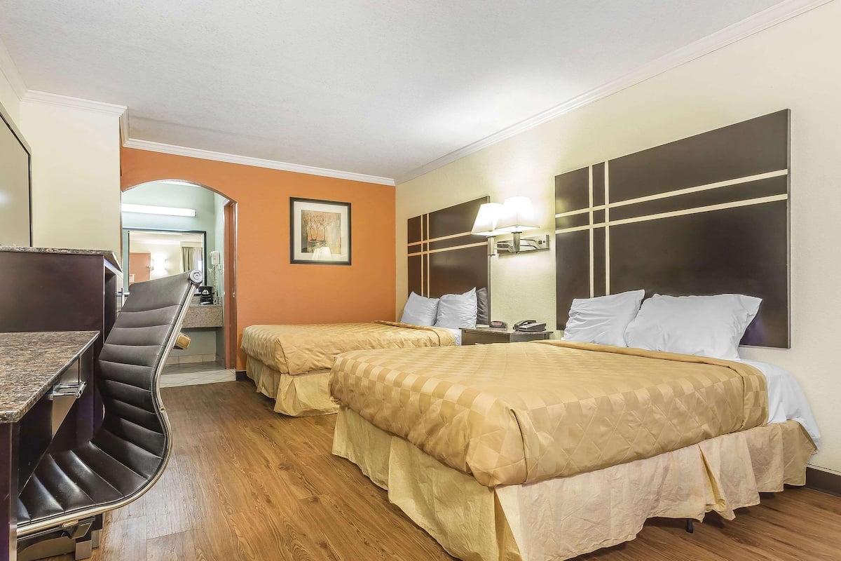 A hotel room with two beds, a desk, and a chair.