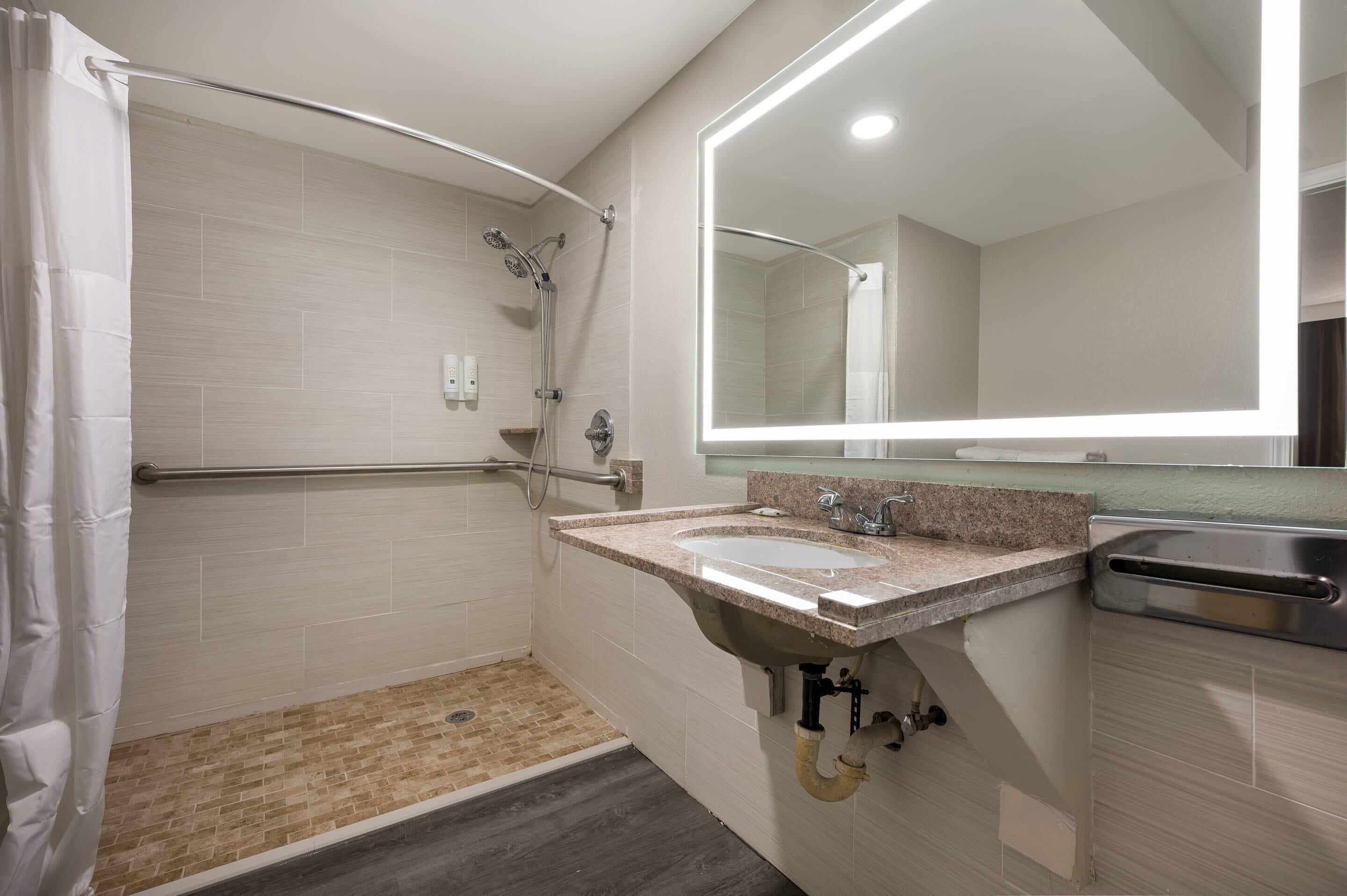 Un baño moderno con ducha, lavamanos y espejo.