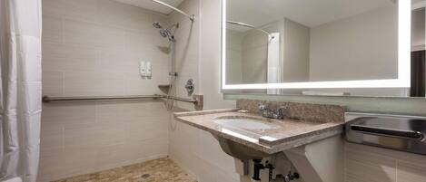 Un baño moderno con ducha, lavamanos y espejo.