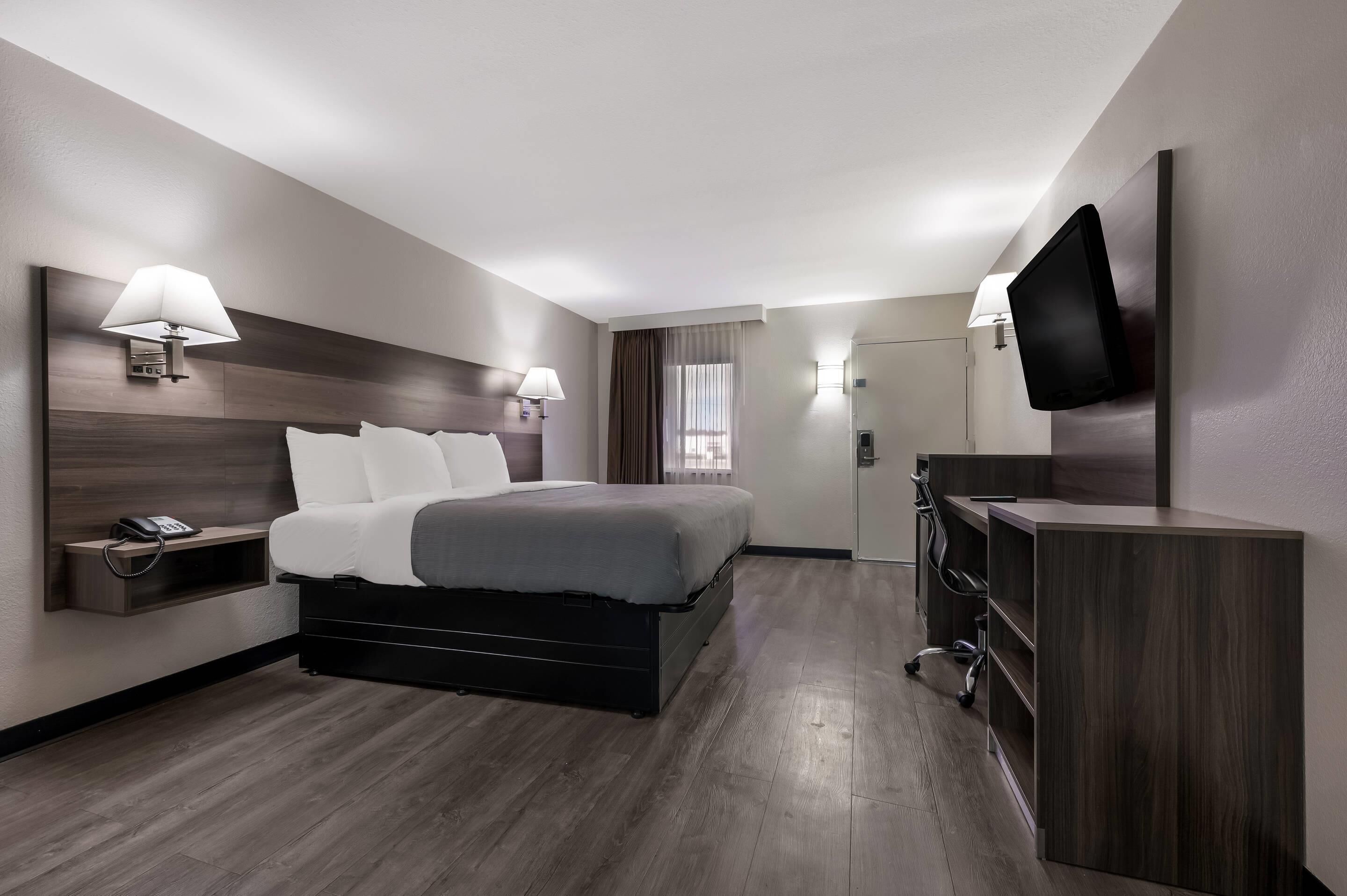 Une chambre d’hôtel moderne équipée d’un lit, de lampes de chevet, d’un bureau, d’un téléviseur à écran plat et d’un téléphone.