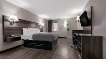 Una moderna camera d'albergo con un letto, abat-jour, una scrivania, una TV a schermo piatto e un telefono.