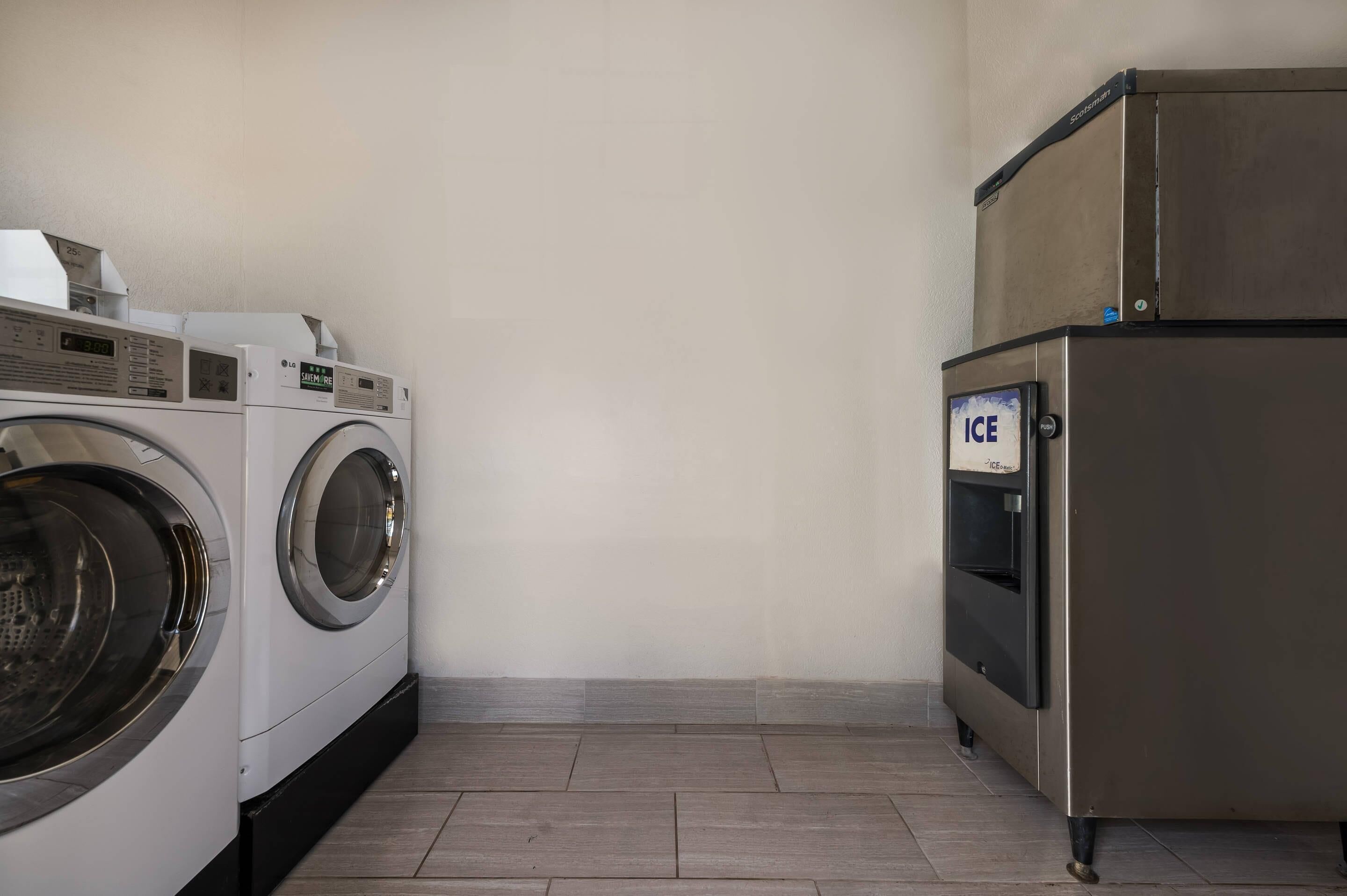Een wasserette met een wasmachine, droger en ijsmachine.