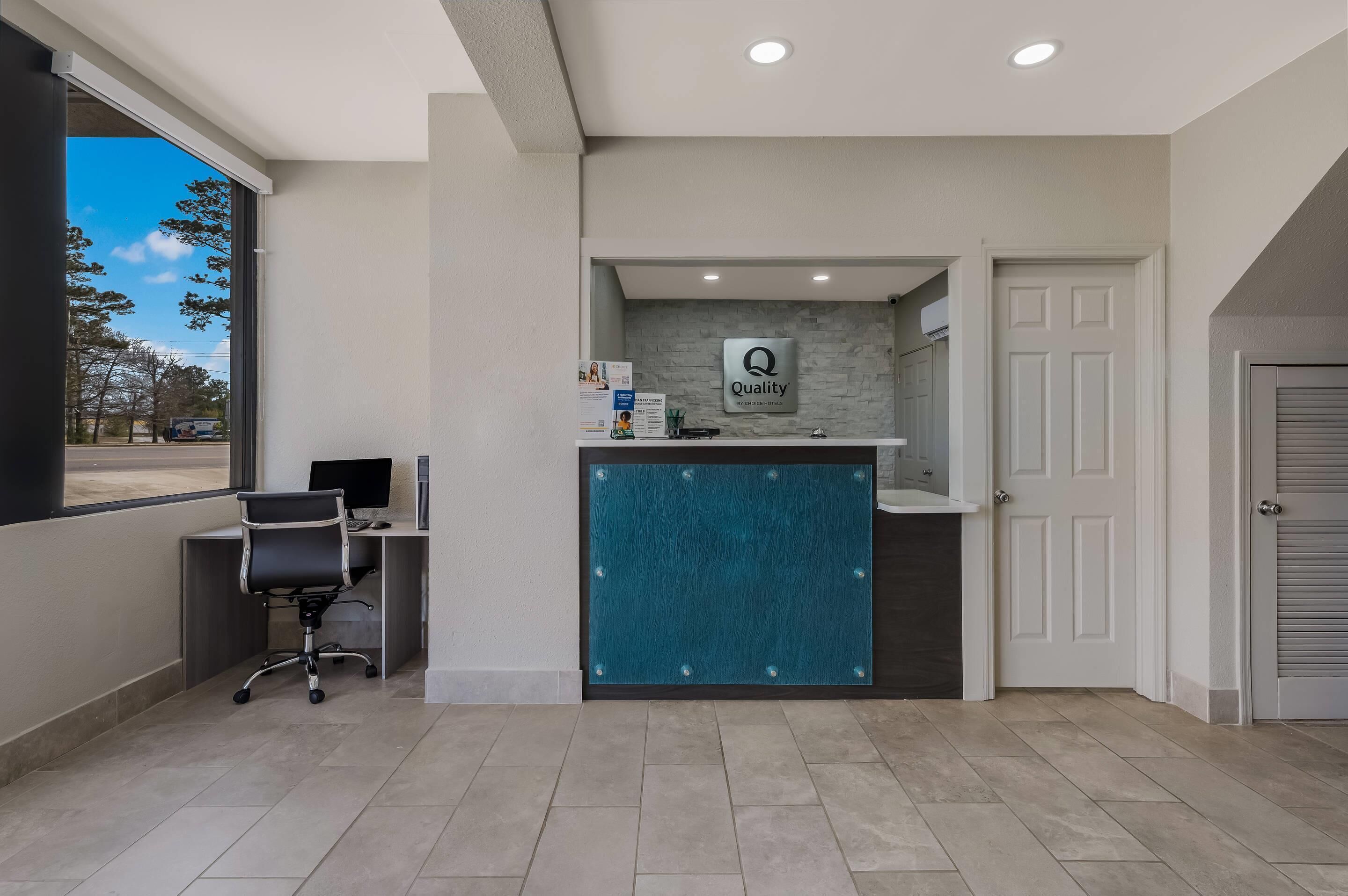A reception desk with a 'Quality' sign, a computer, and a chair.