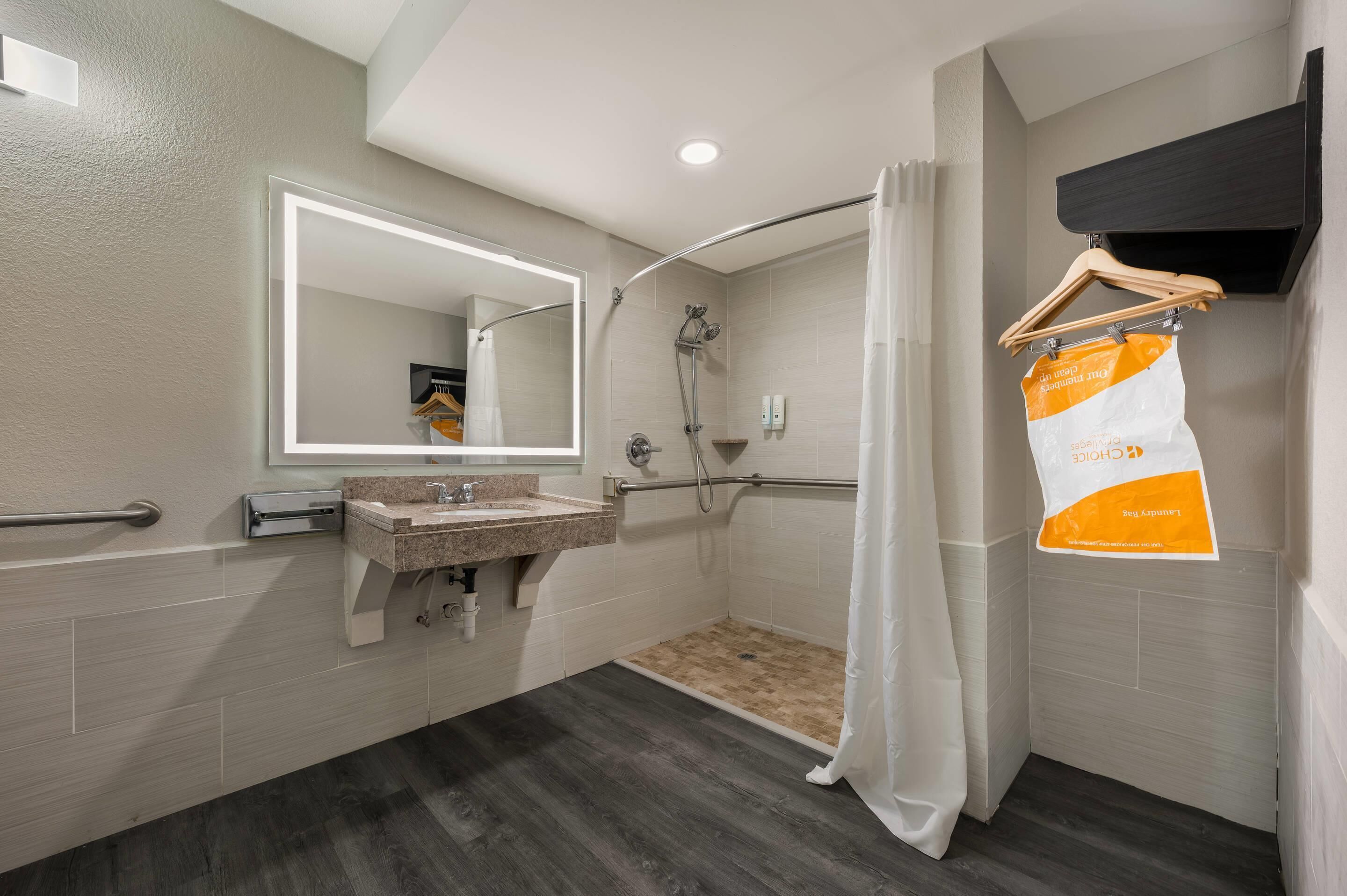 A modern bathroom with a shower, a sink, a mirror, and a towel rack.