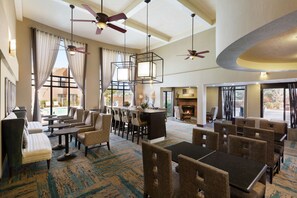 A spacious hotel lobby with multiple seating areas, a bar, and a fireplace. - Hampton Inn Sedona (Sedona)
