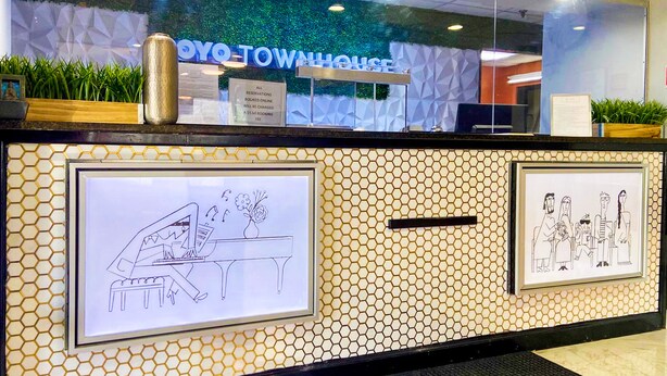 A reception desk with a 'YOYO TOWNHOUSE' sign, framed artwork, and a plant on the counter.