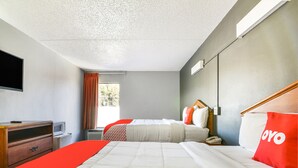 A hotel room with a bed, a bedside table, a TV, and a window with curtains.