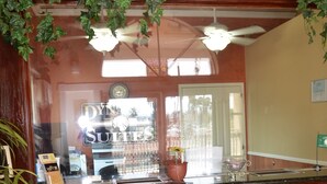 A reception desk with a wooden finish, a ceiling fan, and a potted plant. - Dynasty Suites Hotel Riverside (Riverside)