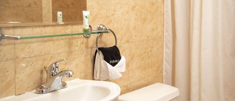 A bathroom with a sink, toilet, and a glass shelf with toiletries.